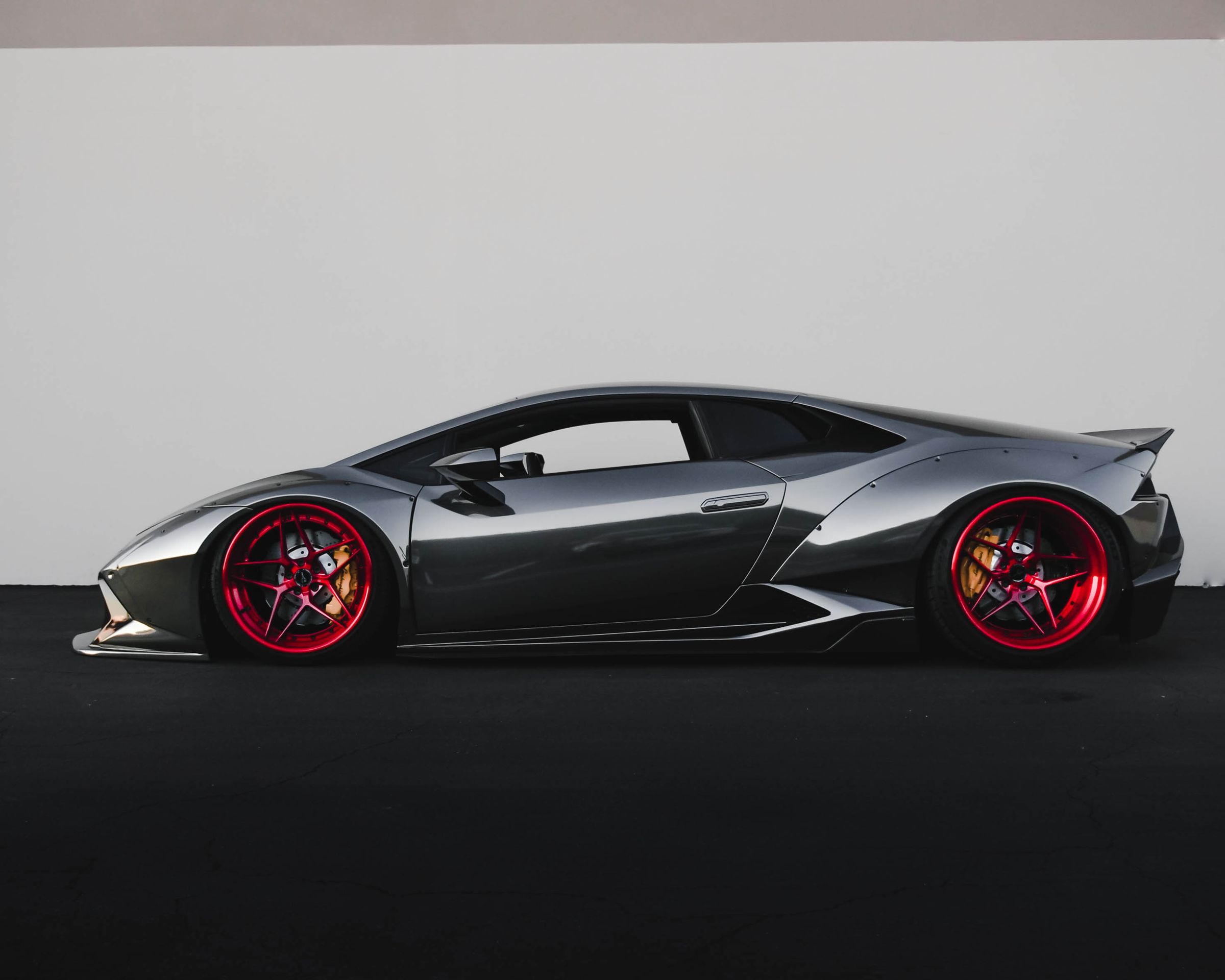 Orange Lamborghini under bright daylight with clear body, wheels, and headlights.